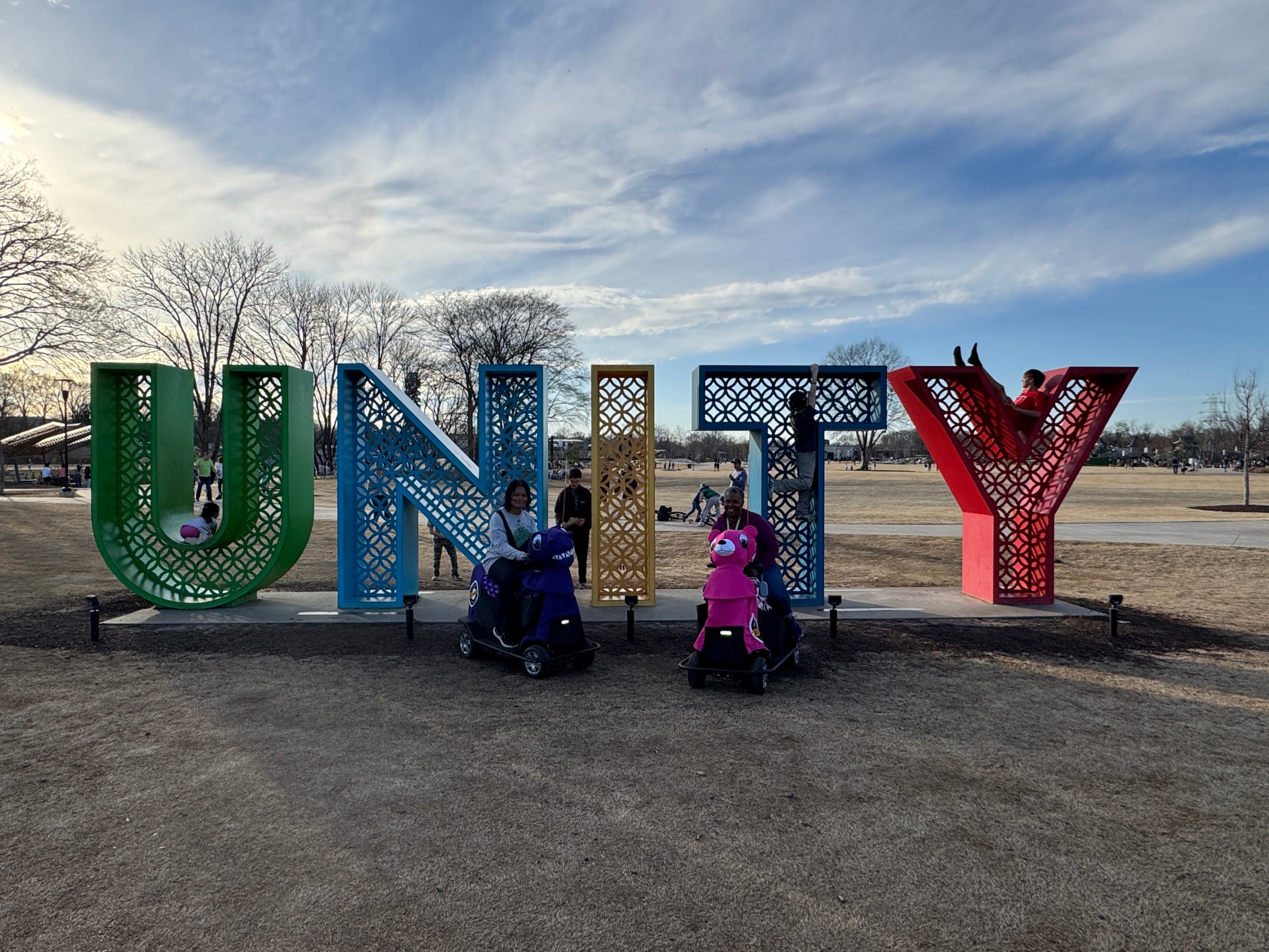 a group of kids in a grassy field with Cadillac Ranch in the background
