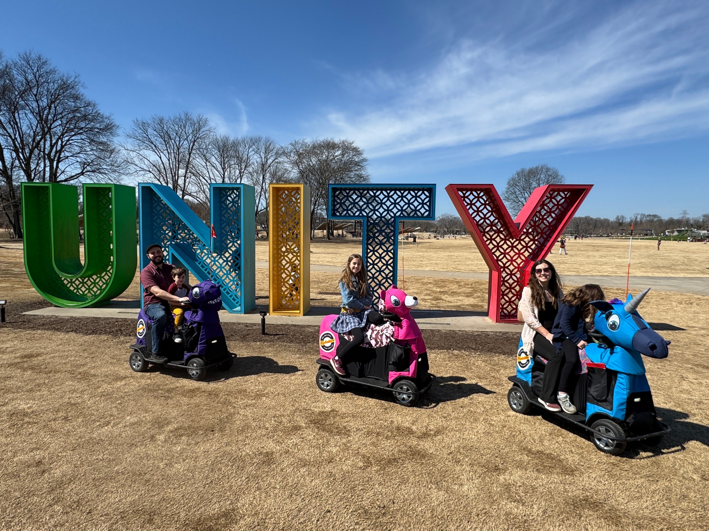 a group of people sitting on a motorcycle with Cadillac Ranch in the background