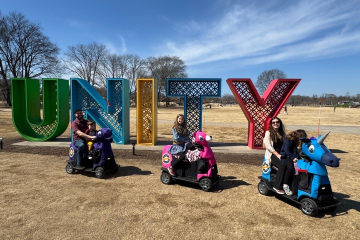 a group of people sitting on a motorcycle with Cadillac Ranch in the background