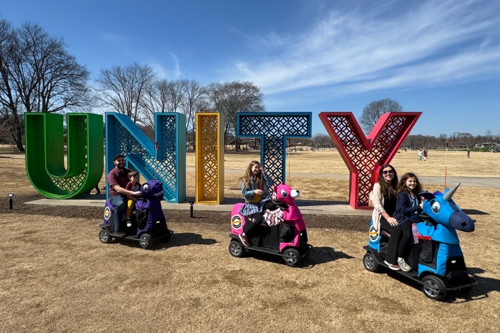 a group of people that are sitting in the grass with Cadillac Ranch in the background